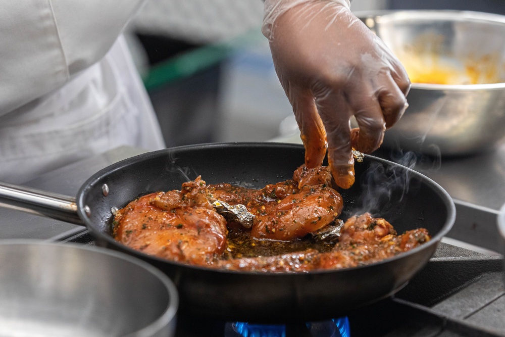 Spc Jacquay Clark places chicken in the pan