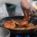 Spc Jacquay Clark places chicken in the pan