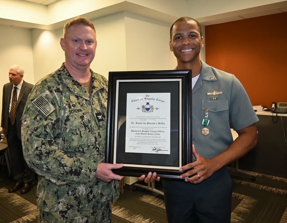 Capt. Cory Schemm, commanding officer, NAVSUP FLC San Diego, presents Lt. Raoni da Paixao e Silva, Brazilian Navy, with his appointment as an Honorary U.S. Supply Corps officer during a ceremony.