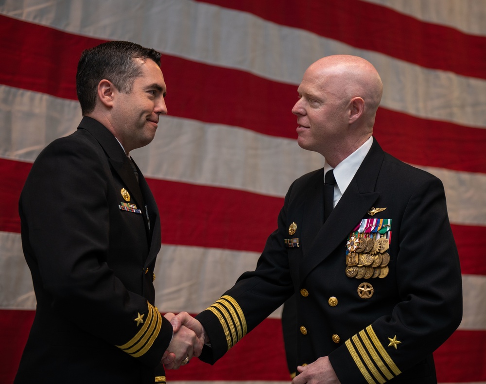 Capt. Raymond Barnes congratulates Cmdr. Matthew Starr