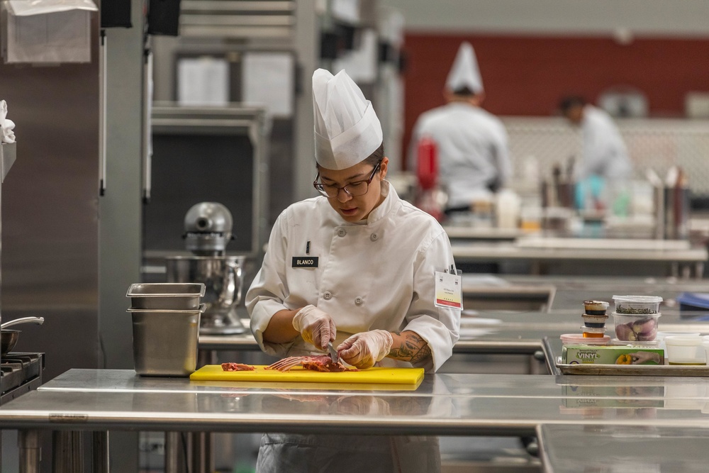 Warrant Officer 1 Daniella Blanco cuts a rack of lamb