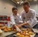 Sgt. 1st Class Jeffery Vaughan helps Warrant Officer 1 Daniella Blanco set up a bread display