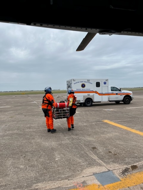 A Coast Guard Air Station Houston MH-65 Dolphin helicopter crew transports a 48-year-old man to awaiting emergency medical services personnel at Scholes International Airport in Galveston, Texas, Mar. 21, 2023. The man was medevaced off the Prism Diversity, a 981-foot tanker vessel, 35 miles south of Galveston, and taken to the University of Texas Medical Branch in Galveston by EMS personnel. (U.S. Coast Guard photo courtesy, Air Station Houston)