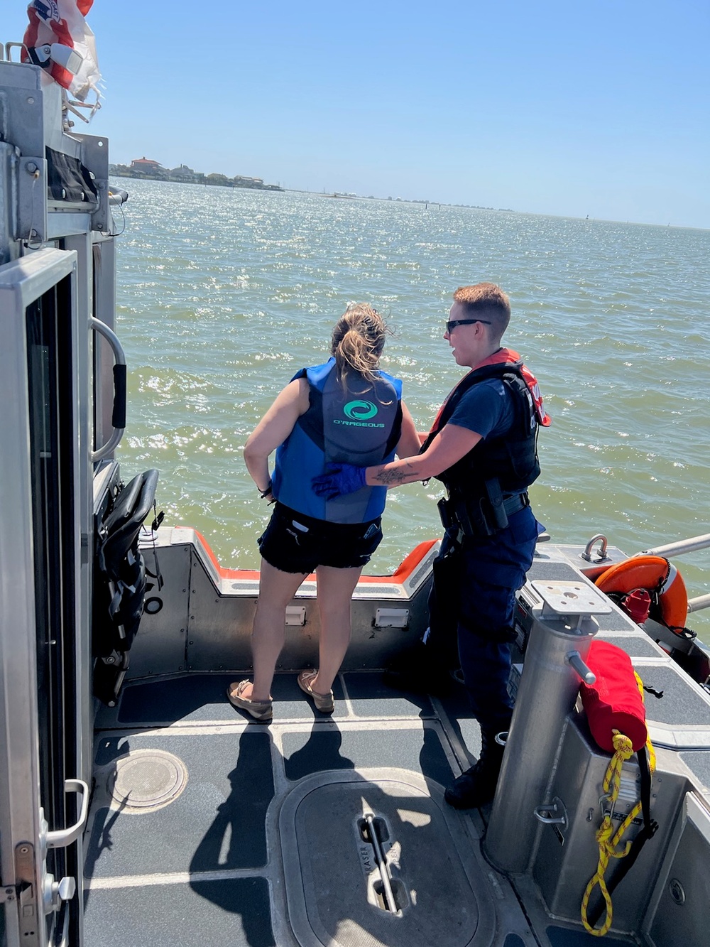 A Coast Guard Station Galveston 29-foot Response Boat–Small crewmember renders assistance to an ailing woman near the Galveston Causeway Bridge in Galveston, Texas, March 22, 2023. The woman needed medical attention and the boat crew transferred her to emergency medical services personnel waiting at Galveston Bait and Tackle. (U.S. Coast Guard photo, courtesy Station Galveston)