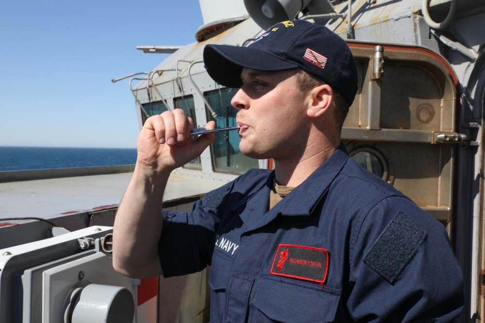 Sailor aboard USS Ramage (DDG 61) pipes while standing port lookout watch