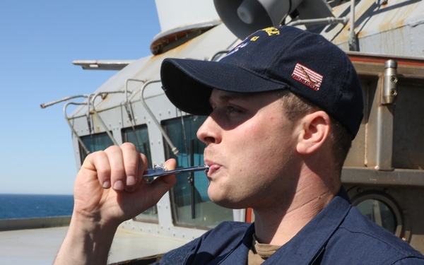 Sailor aboard USS Ramage (DDG 61) pipes while standing port lookout watch