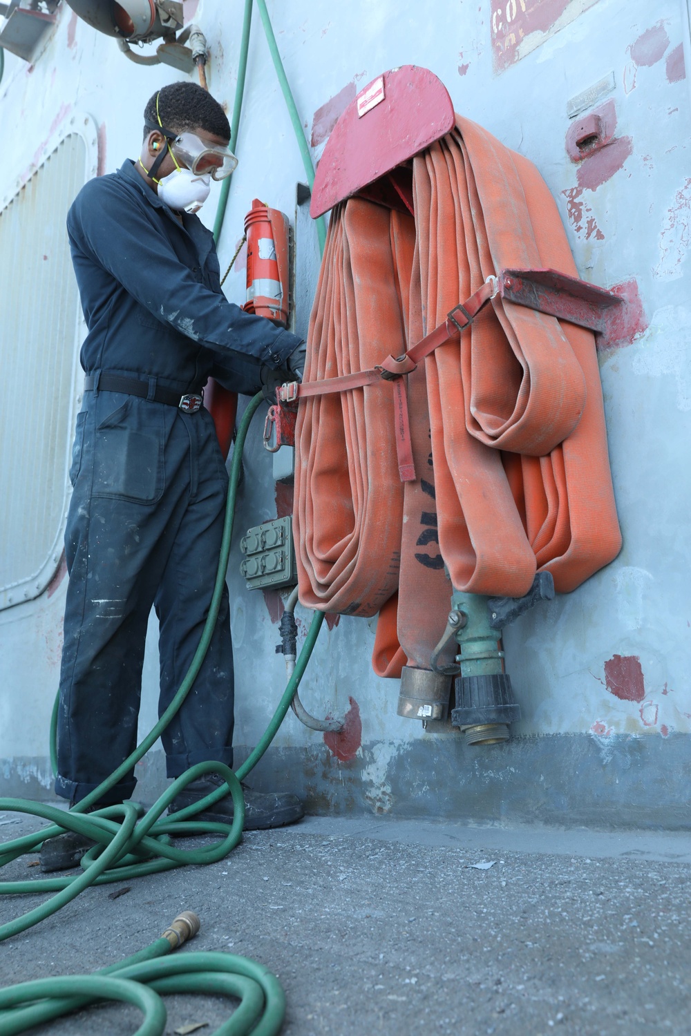 Sailor aboard USS Ramage (DDG 61) performs hull maintenance