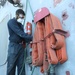 Sailor aboard USS Ramage (DDG 61) performs hull maintenance