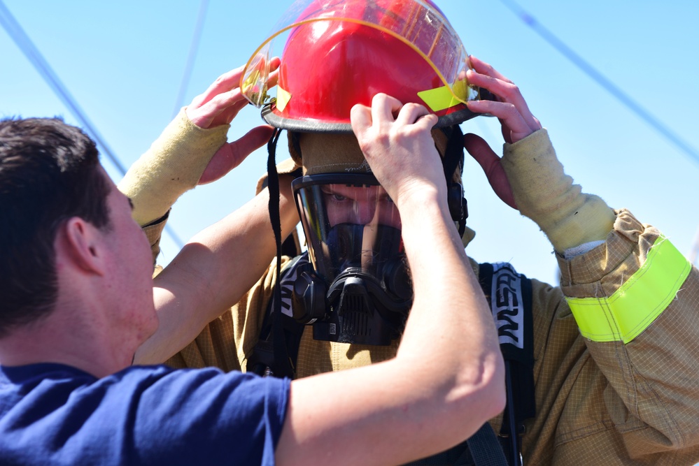 USCGC Eagle personnel don firefighting equipment during a drill while underway in the Atlantic Ocean