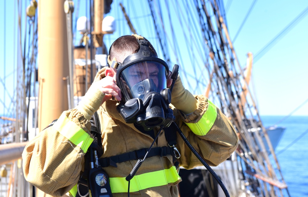 USCGC Eagle personnel don firefighting equipment during a drill while underway in the Atlantic Ocean