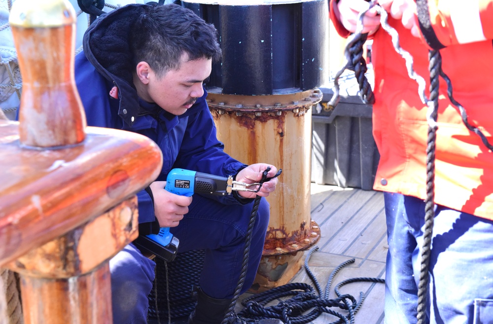 USCGC Eagle crew member splices ratline while underway in the Atlantic Ocean