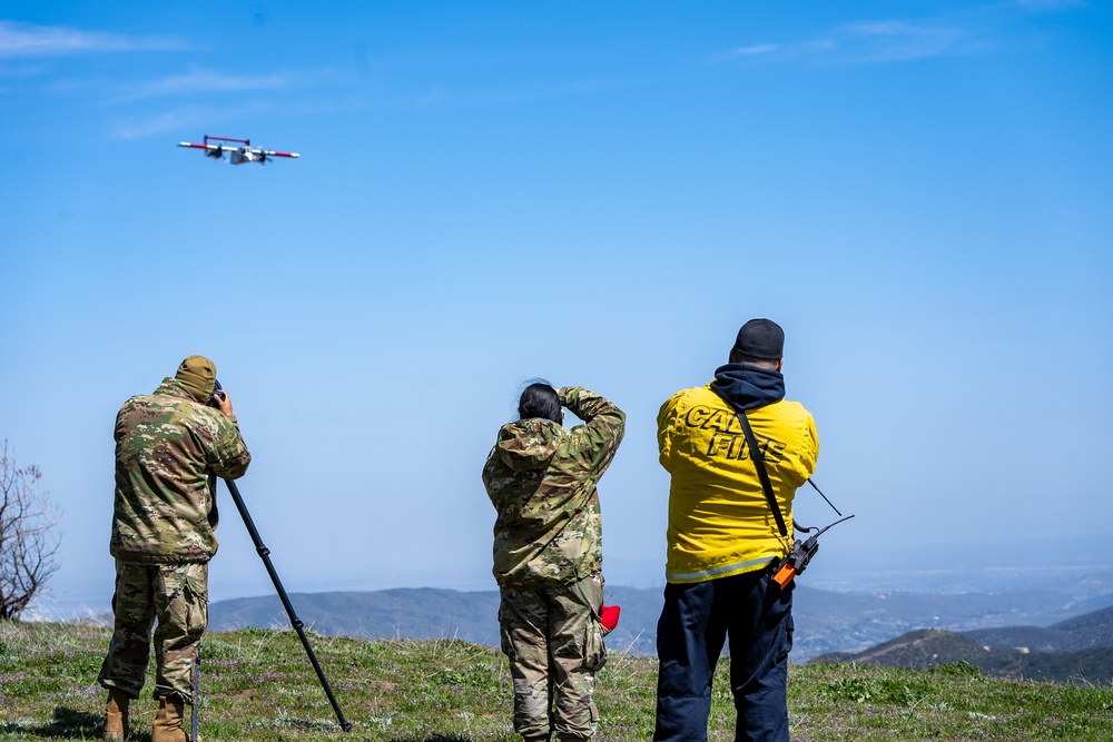 Two public affairs specialists from California Air National Guard and a CAL FIRE Fire Captain, atop a hill near Green Valley, Calif. April 14, 2023