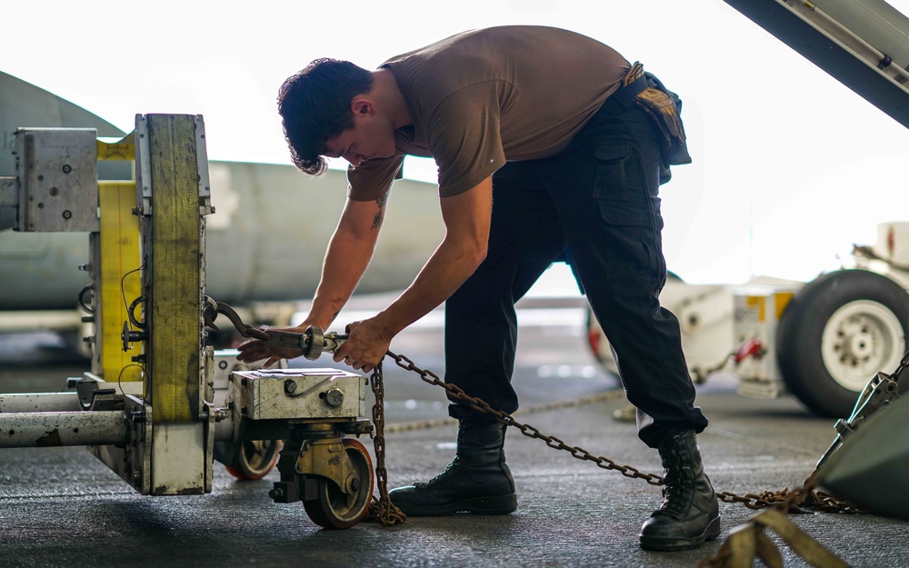 Sailor checks chains on a jet aboard USS Carl Vinson