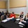 DPAA hosts Chicago FMU A professional meeting or workshop is taking place in a conference room with multiple round tables. Several groups of people are engaged in discussions, reviewing documents, and working with laptops. The setting appears to be a formal business or academic event based on attire and materials present.