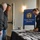 DPAA hosts Chicago FMU A U.S. Army soldier in dress uniform is staffing a table at a Defense POW/MIA Accounting Agency (DPAA) Family Member Update event. Two civilian men are approaching the registration or information table, which is covered with what appear to be name tags or printed materials. The event appears to be held in a hotel or conference center setting.