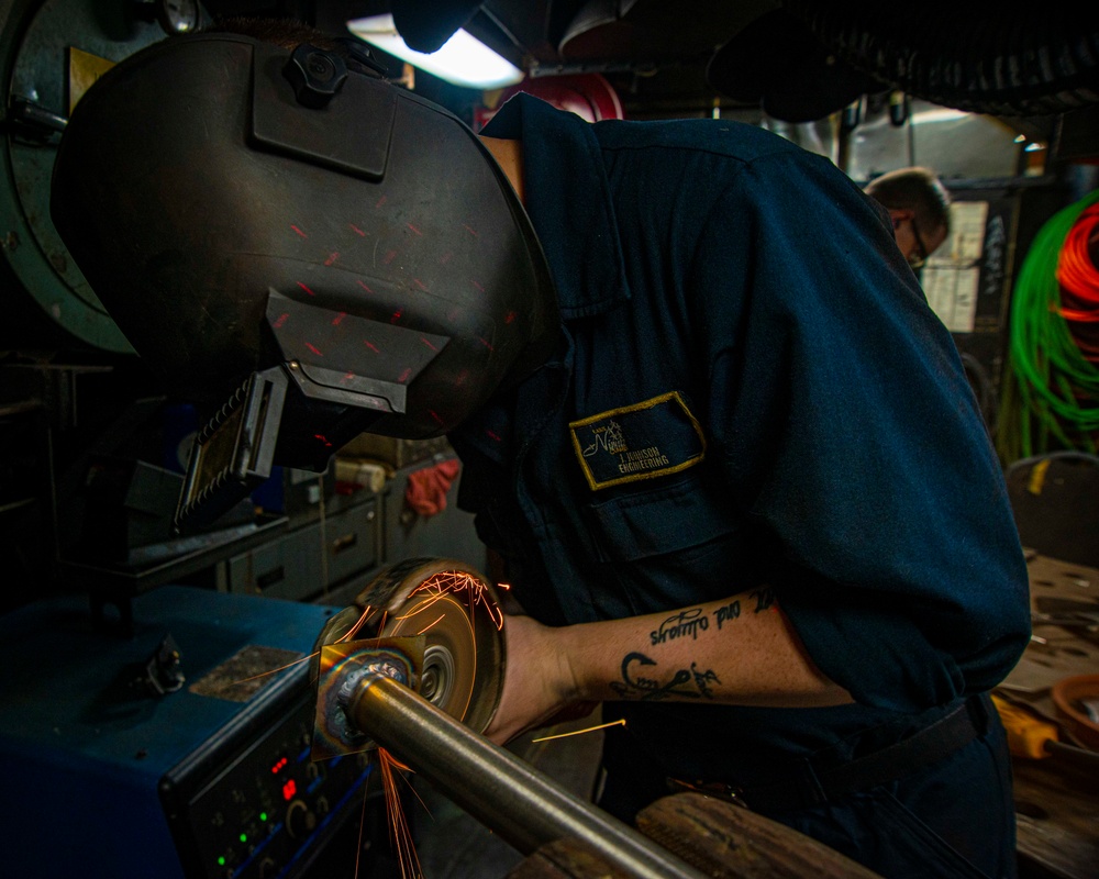 Sailor Grinds Pipe Welds