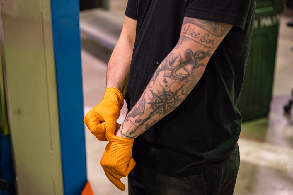 914th vehicle maintenance Airman puts on gloves before oil change