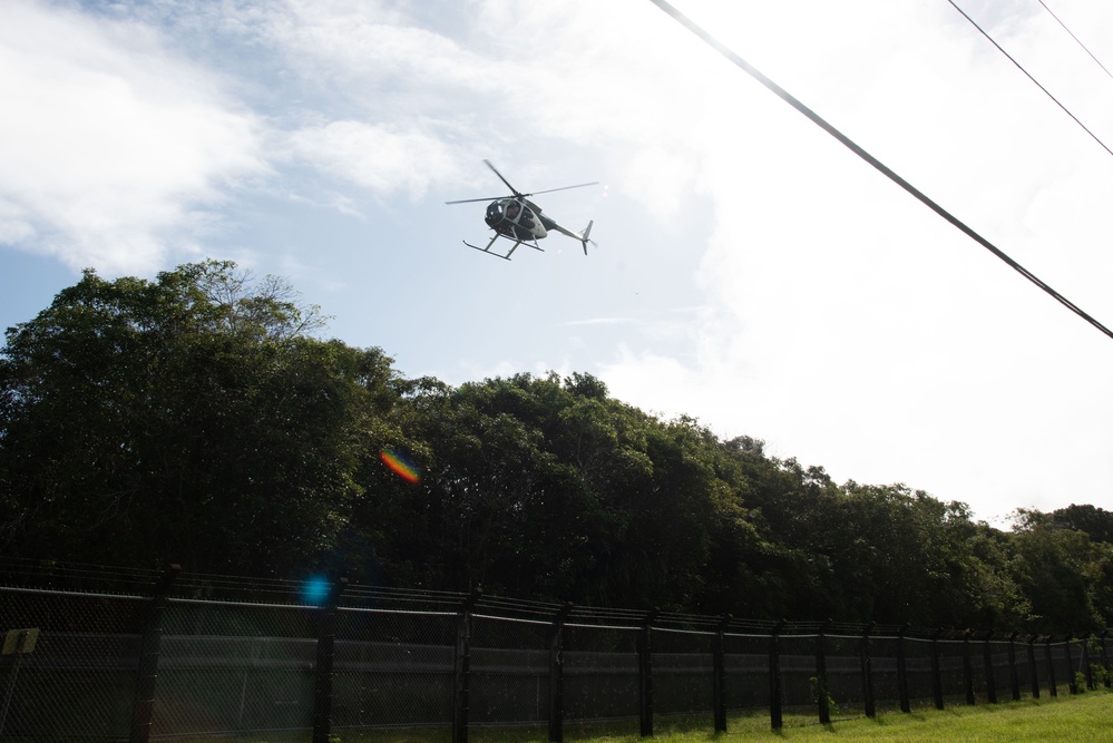 UH-6 helicopter makes a pass over a fenced habitat management unit on Andersen Air Force Base