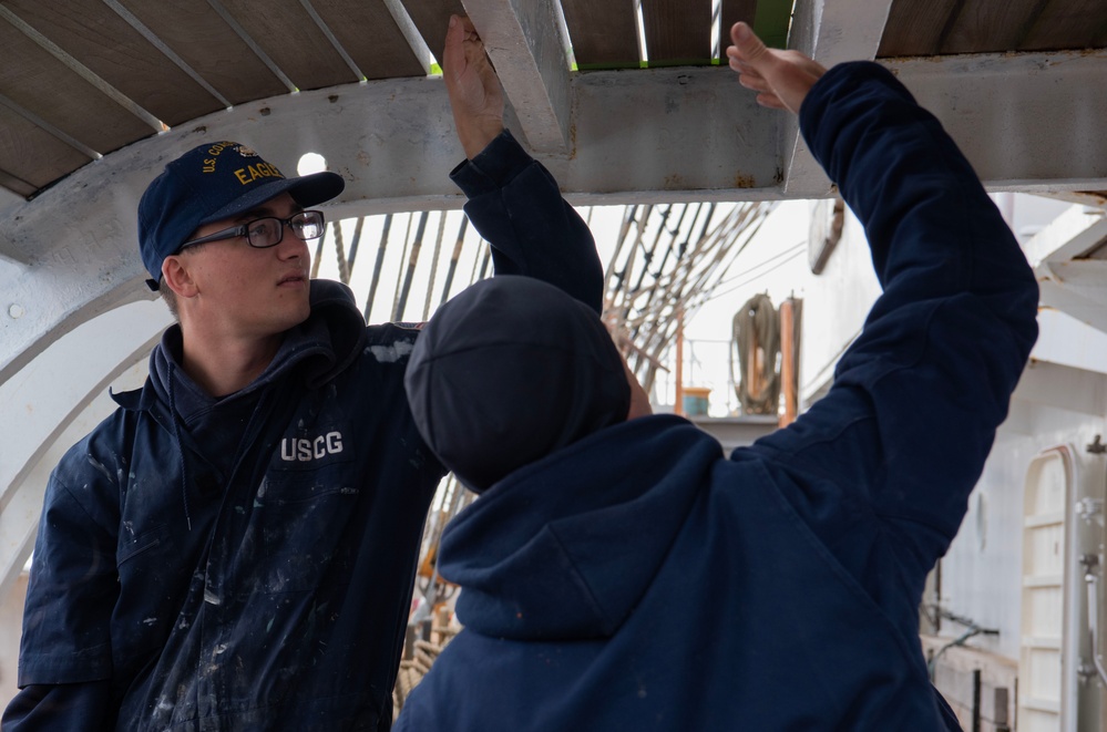 USCGC Eagle crew members maintain upkeep of the training vessel while underway