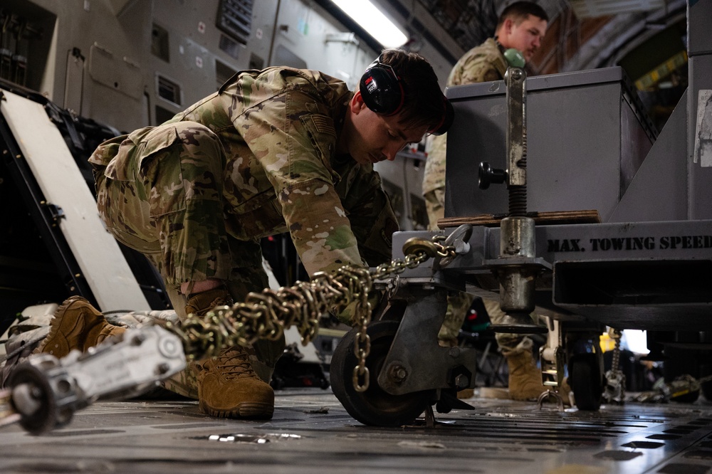 190th Air Refueling Wing airman tightens down cargo on C-17