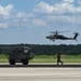 AH-64 Apache attack helicopter flies by F-16 Fighting Falcon on flightline