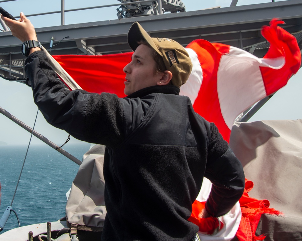 Sailor Lowers Signal Flags Following Port Transit