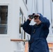 Coast Guard Cadet aboard USCGC Eagle scans horizon with binoculars