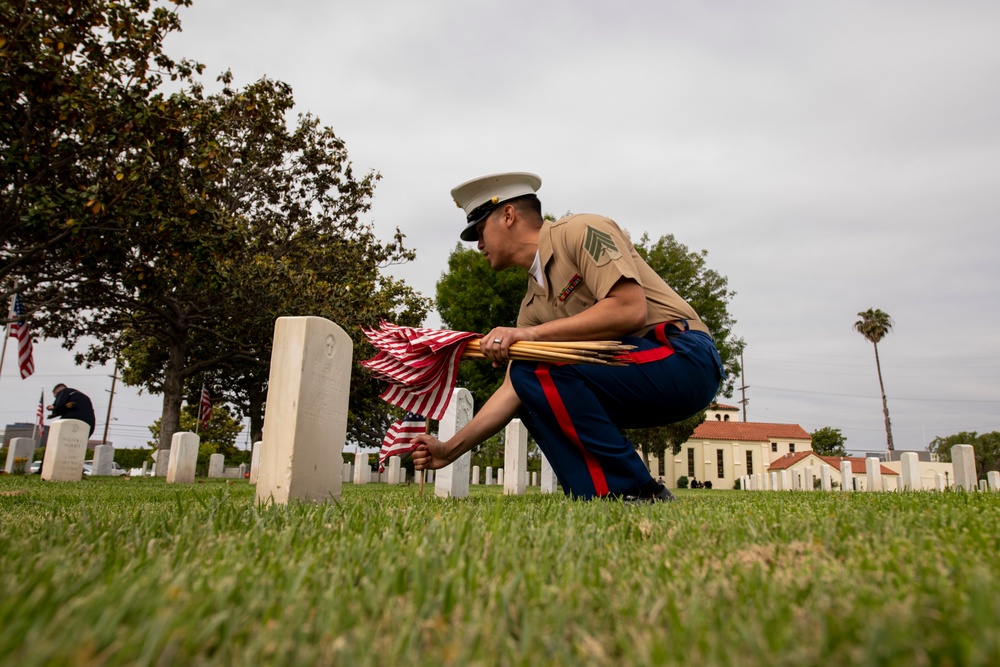 Sailors and Marine place flag at service members graves