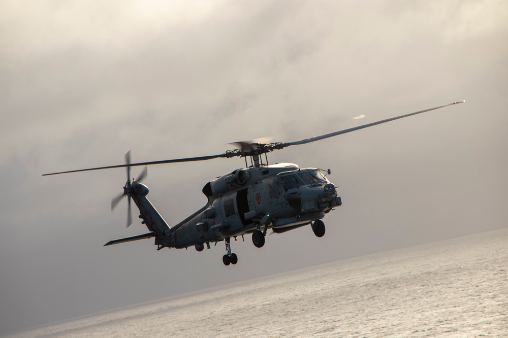 MH-60R Sea Hawk Helicopter Flies Near The Aircraft Carrier USS Nimitz
