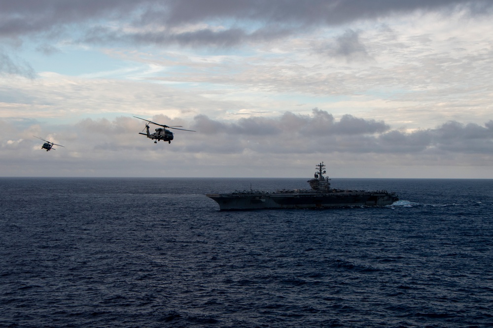 MH-60R Sea Hawk Helicopters Fly Near The Aircraft Carrier USS Nimitz