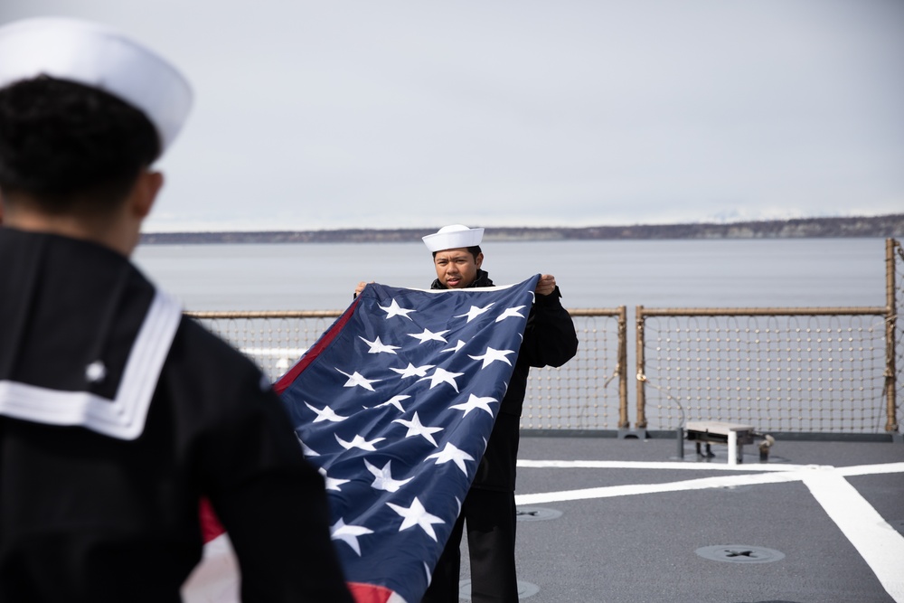 USS Harpers Ferry (LSD 49) sailors fold the ensign as the ship gets underway