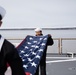 USS Harpers Ferry (LSD 49) sailors fold the ensign as the ship gets underway