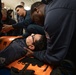 Electronic Technician 2nd Class Andre Woods assists sailors in stretcher bearer training