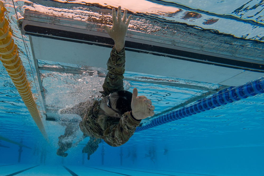 Army Reserve Sgt. Denzel Torres swims under an obstacle