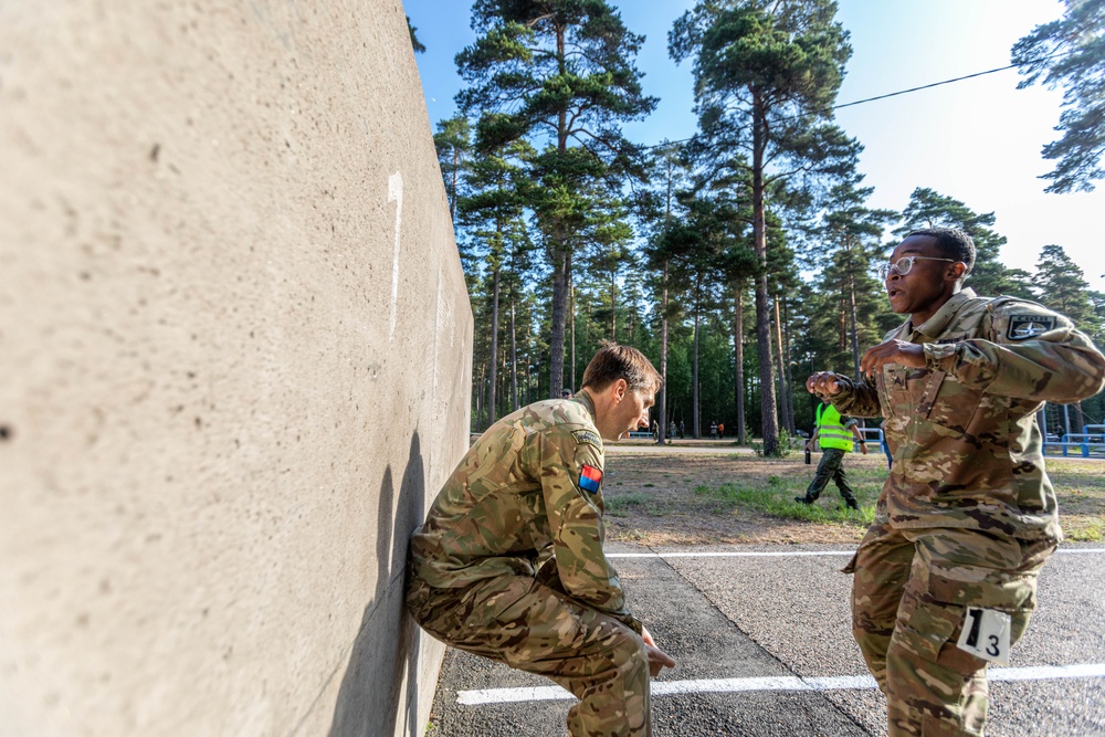 British Lt. Kristopher Smith assists U.S. Army Reserve Sgt. Alecia Jones with an obstacle