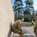 British Lt. Kristopher Smith assists U.S. Army Reserve Sgt. Alecia Jones with an obstacle