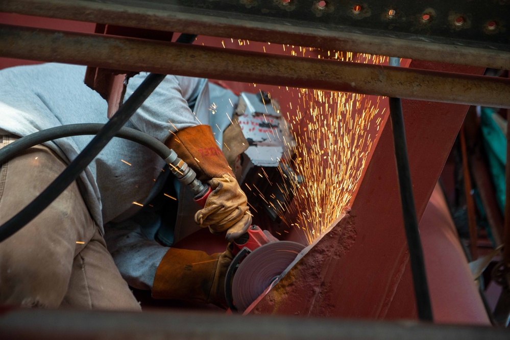 Contractor grinds metal onboard the USS John C. Stennis