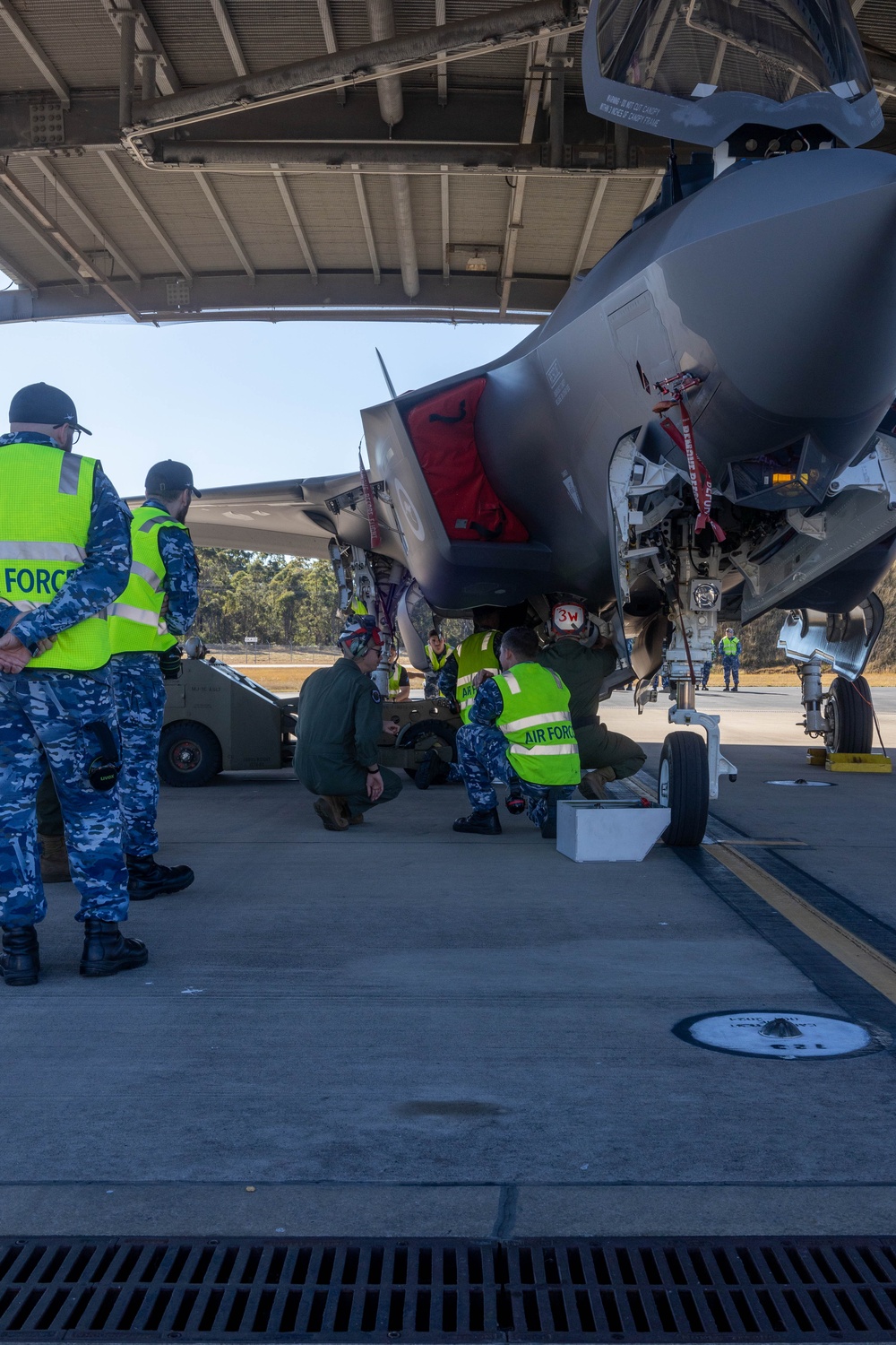 U.S. Marines and Australian Airmen load Missiles on Joint Strike Fighters together  