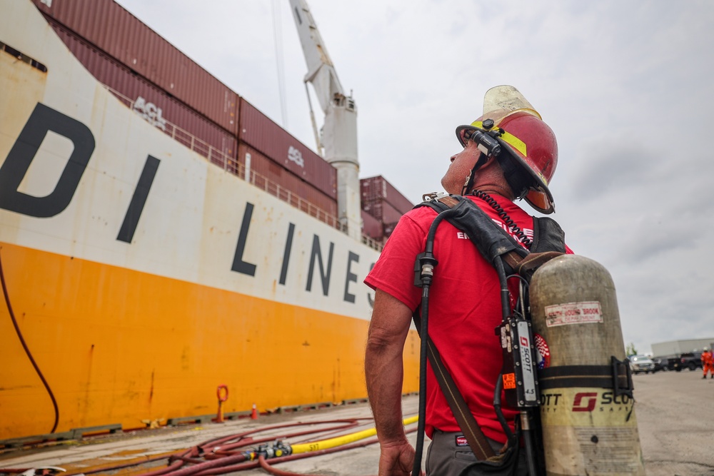 A salvage and marine firefighter from DONJON SMIT observes the scene of the response to the fire on the motor vessel Grande Costa D’Avorio at Port Newark, New Jersey, July 9, 2023. Response and salvage personnel are continuing their response to the fire on the vessel. (U.S. Coast Guard photo by Dan Henry)