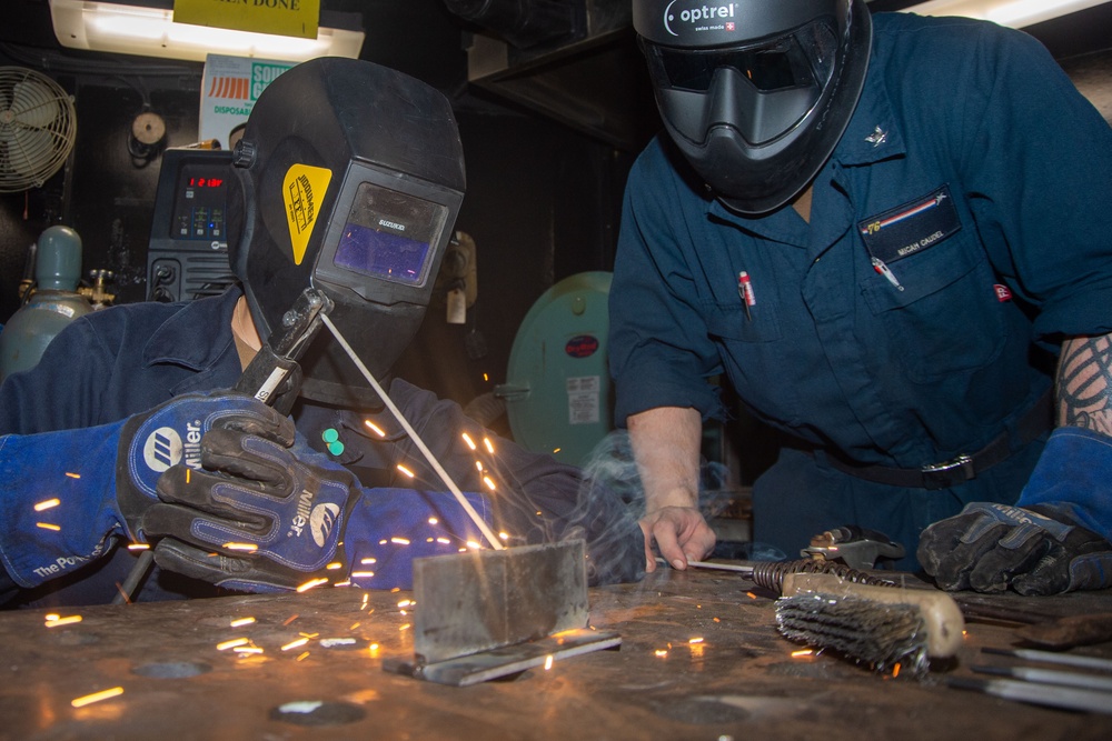 USS Ronald Reagan (CVN 76) Sailors train midshipmen how to weld and use a lathe