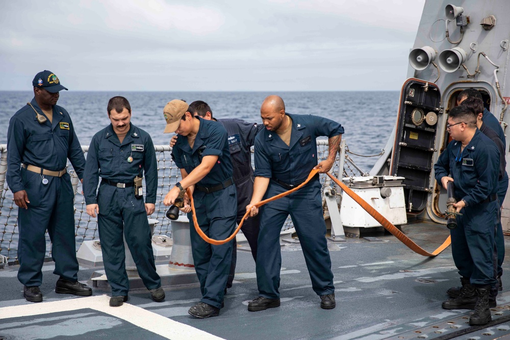 Crash and salvage team members train by fighting a simulated fire aboard USS Ralph Johnson.