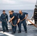 Crash and salvage team members train by fighting a simulated fire aboard USS Ralph Johnson.