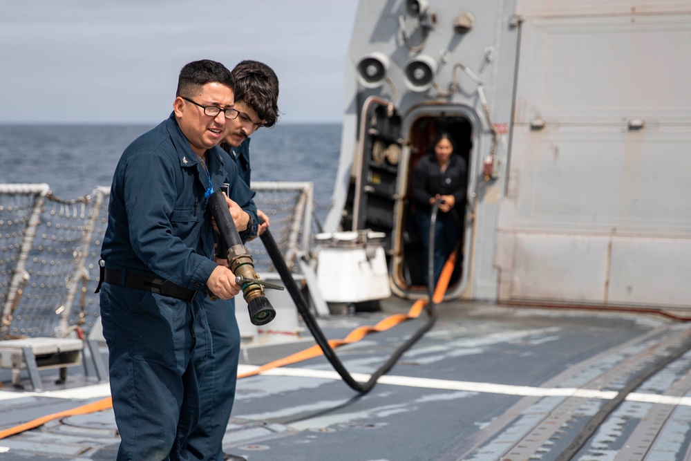 Crash and salvage team members train by fighting a simulated fire aboard USS Ralph Johnson.