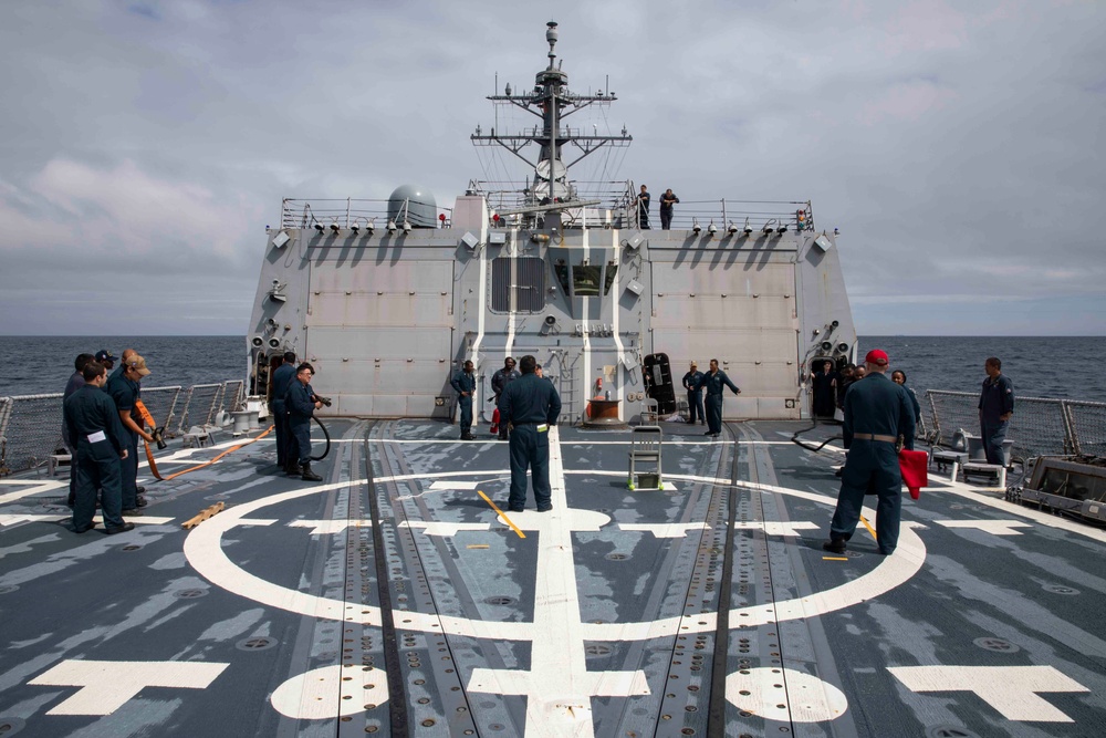 Crash and salvage team members train by fighting a simulated fire aboard USS Ralph Johnson.