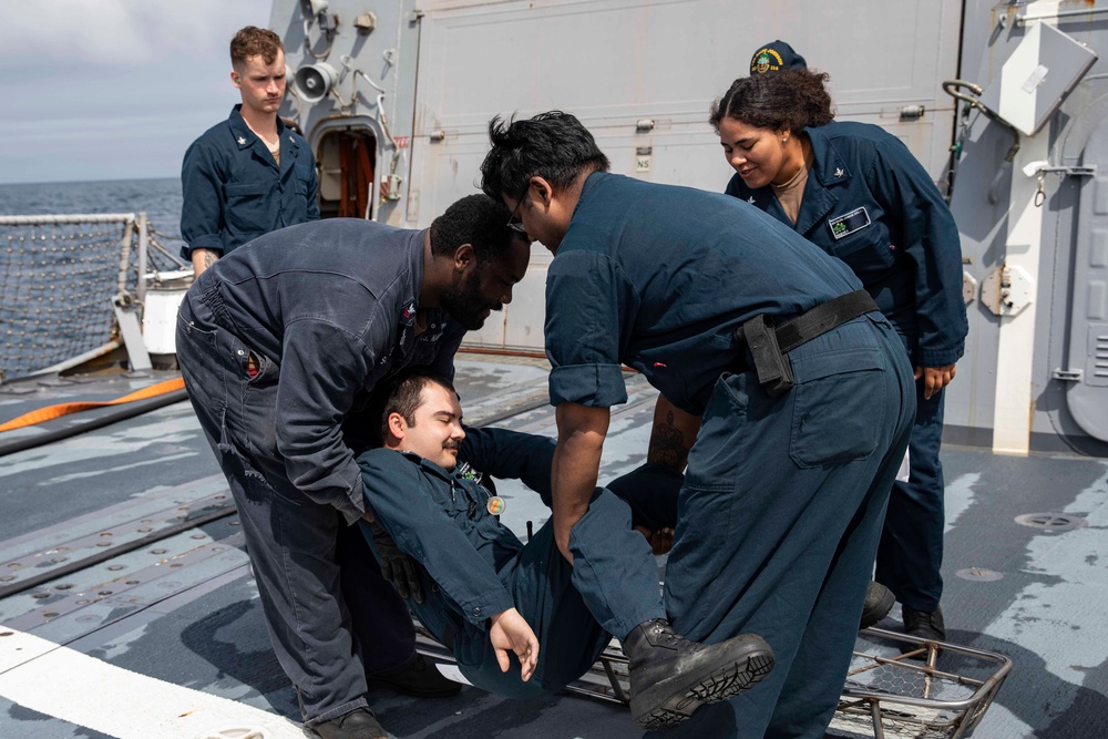 Crash and salvage team members train by fighting a simulated fire aboard USS Ralph Johnson.