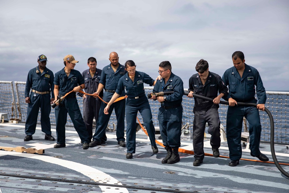 Crash and salvage team members train by fighting a simulated fire aboard USS Ralph Johnson.