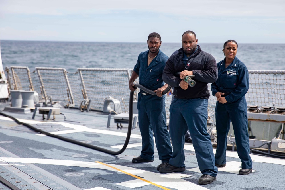 Crash and salvage team members train by fighting a simulated fire aboard USS Ralph Johnson.