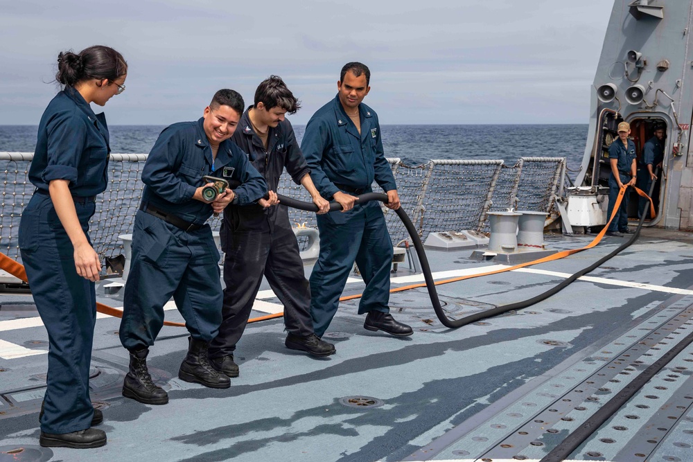 Crash and salvage team members train by fighting a simulated fire aboard USS Ralph Johnson.