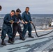 Crash and salvage team members train by fighting a simulated fire aboard USS Ralph Johnson.