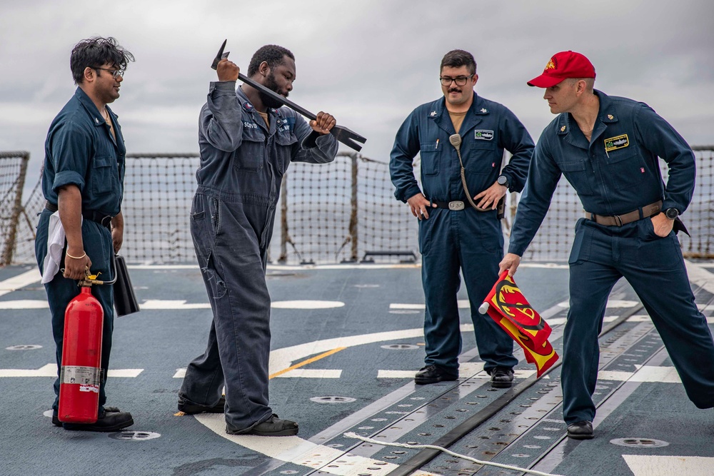 Crash and salvage team members train by fighting a simulated fire aboard USS Ralph Johnson.